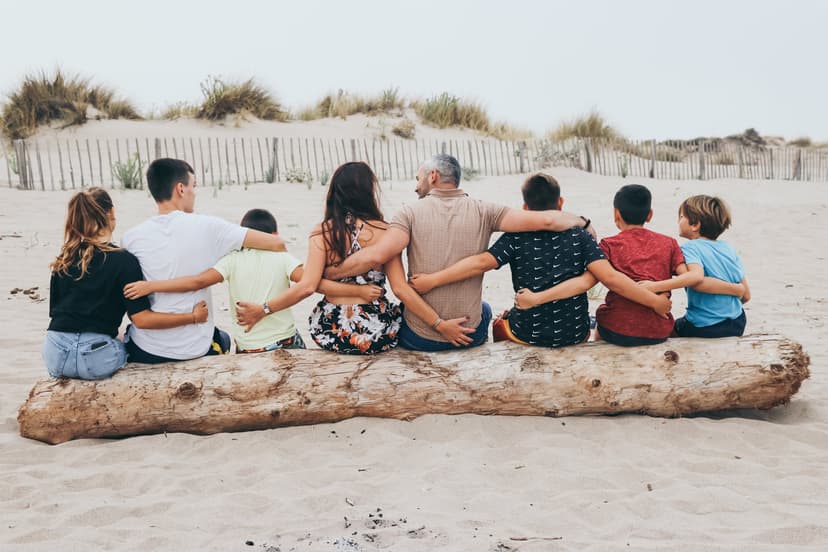 Famille de dos assise sur un tronc d'arbre à la plage