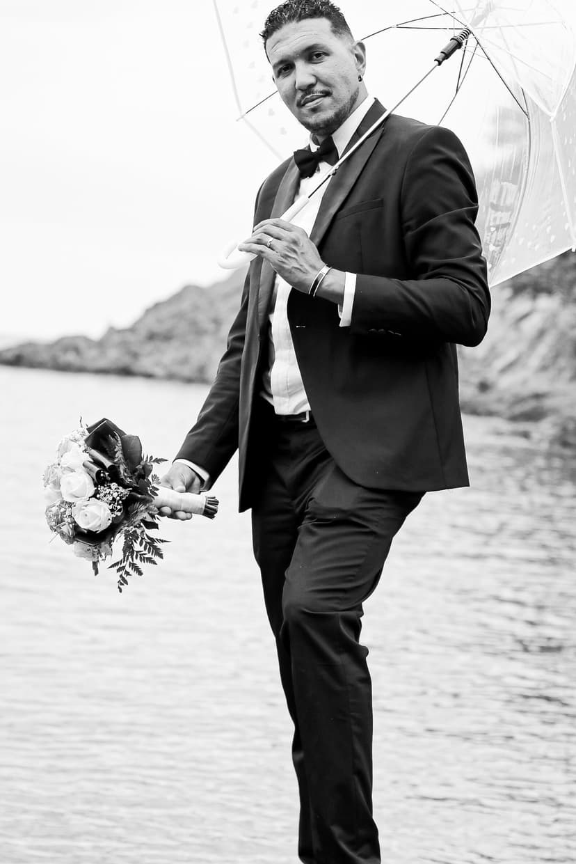 Photographe mariage : marié avec bouquet et ombrelle sur la plage