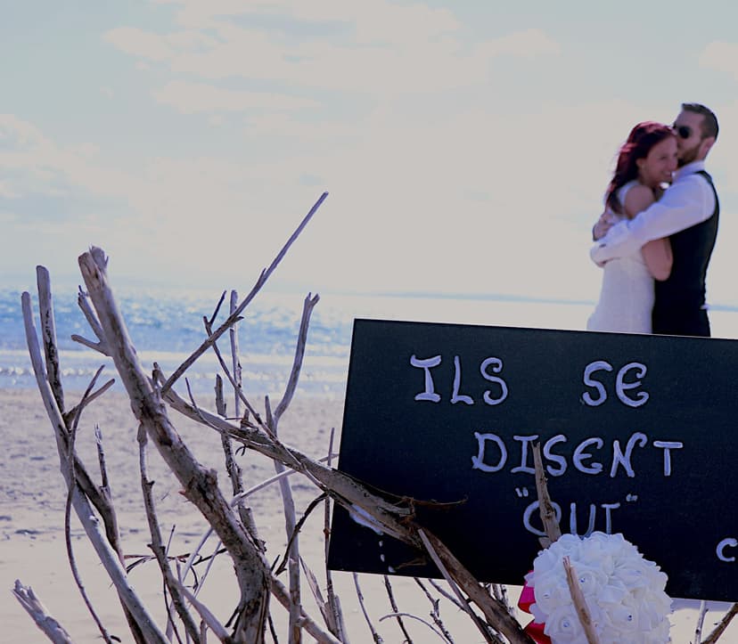 Photographe mariage : couple sur la plage devant le panneau "Ils se disent oui"