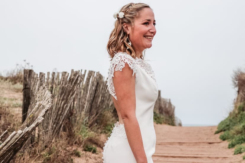 Photographe mariage : mariée souriante sur un chemin de dune