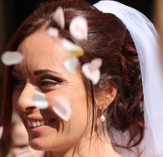 Portrait de mariée souriante sous une pluie de pétales de fleurs